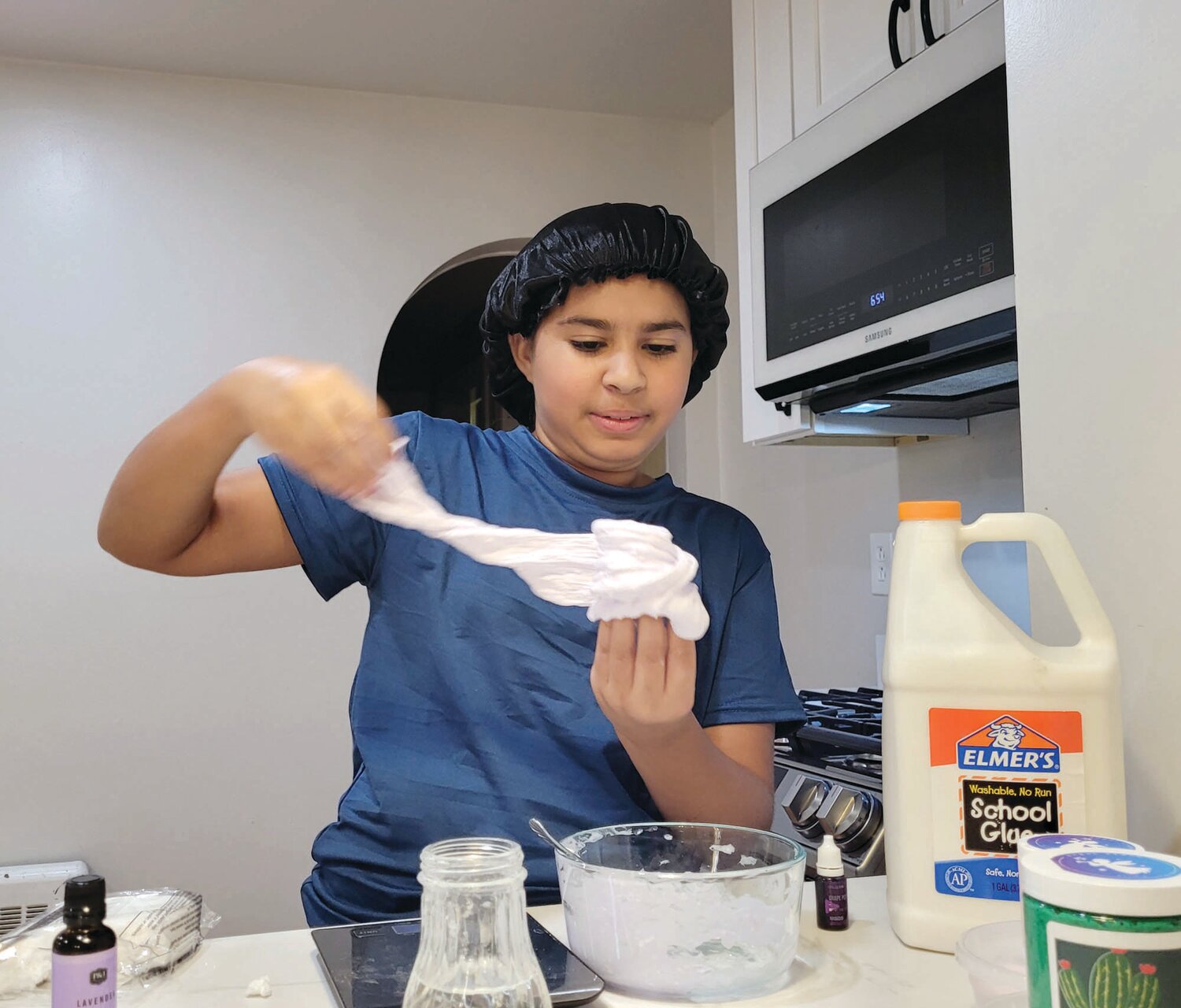 STRESS RELIEF: Santos needs to work the ingredients into the slime. Usually, she wears gloves while making slime for sale. Here, she demonstrates the technique on a sample batch of one of her favorite slimes, Lavender Butter Slime.